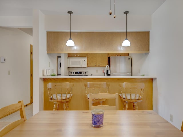 interior space featuring light brown cabinetry, decorative light fixtures, stainless steel electric stove, and fridge