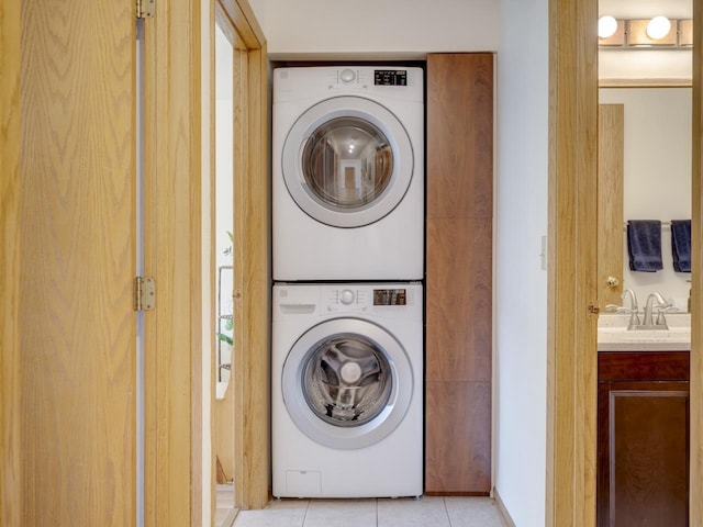 laundry area featuring stacked washer and dryer, sink, and light tile patterned floors