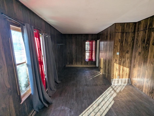 unfurnished room with dark wood-type flooring and wooden walls