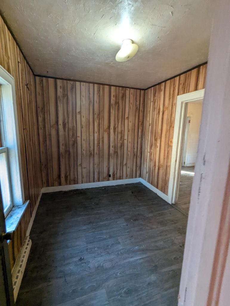 empty room with a baseboard radiator and dark hardwood / wood-style flooring