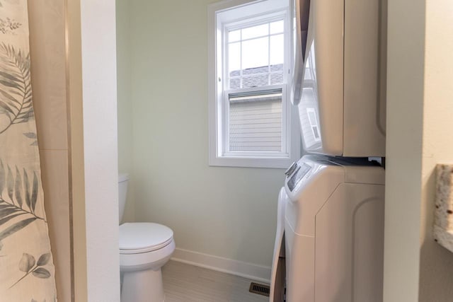 bathroom with stacked washer and dryer and toilet