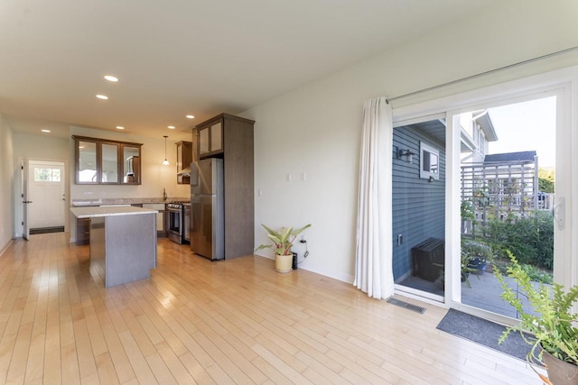 kitchen with stainless steel appliances, hanging light fixtures, a breakfast bar, and light wood-type flooring