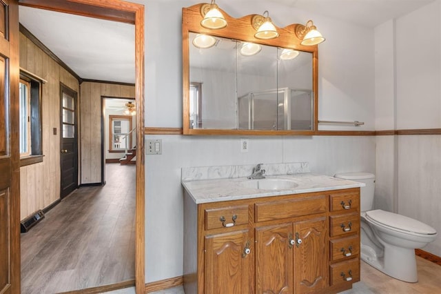 bathroom with hardwood / wood-style floors, vanity, ceiling fan, walk in shower, and toilet