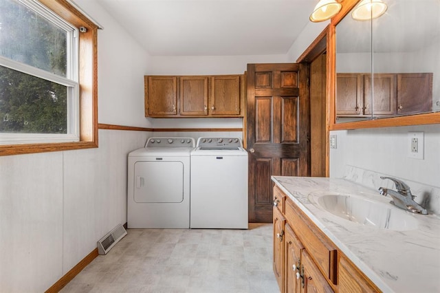 clothes washing area with cabinets, separate washer and dryer, and sink