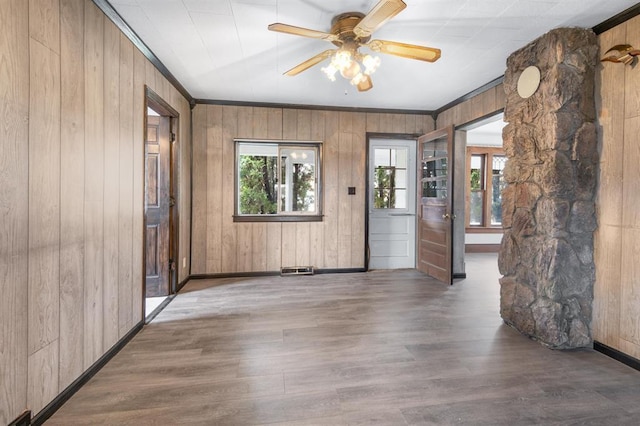 foyer entrance featuring wood-type flooring, wooden walls, ornamental molding, and ceiling fan