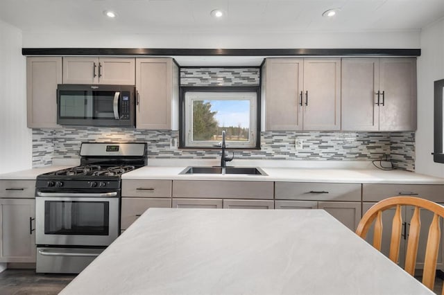 kitchen with tasteful backsplash, sink, gray cabinetry, and appliances with stainless steel finishes