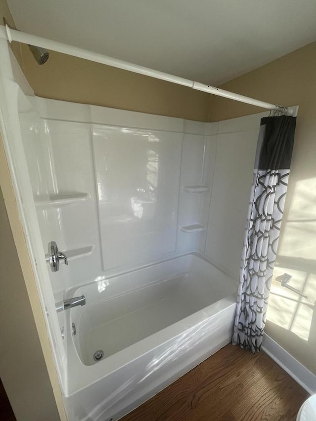 bathroom with hardwood / wood-style flooring and shower / tub combo with curtain