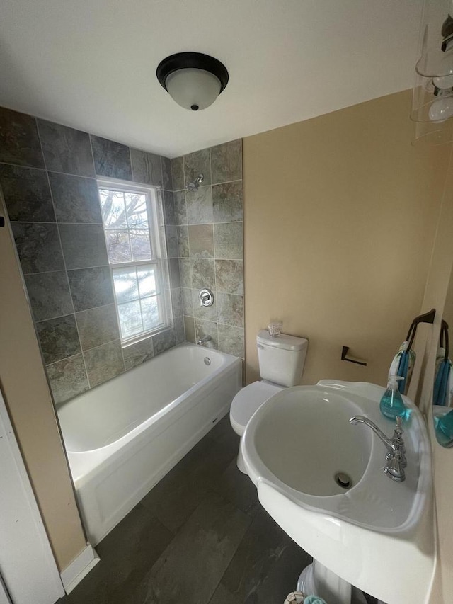 bathroom with tiled shower / bath combo and toilet