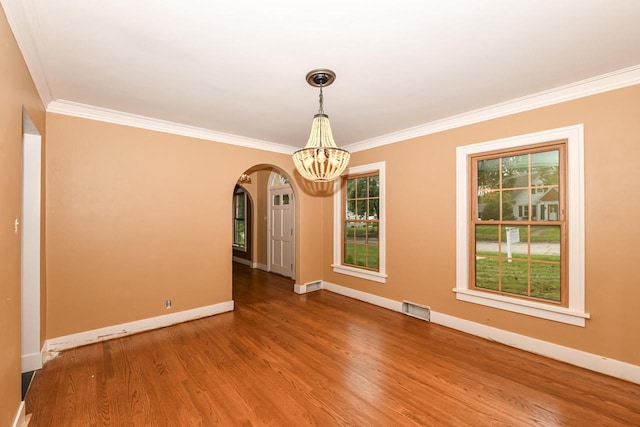 spare room featuring hardwood / wood-style flooring, ornamental molding, and a notable chandelier