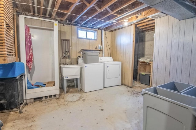 laundry area with washer and clothes dryer, sink, and wooden walls