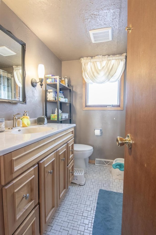 bathroom featuring vanity, toilet, and a textured ceiling