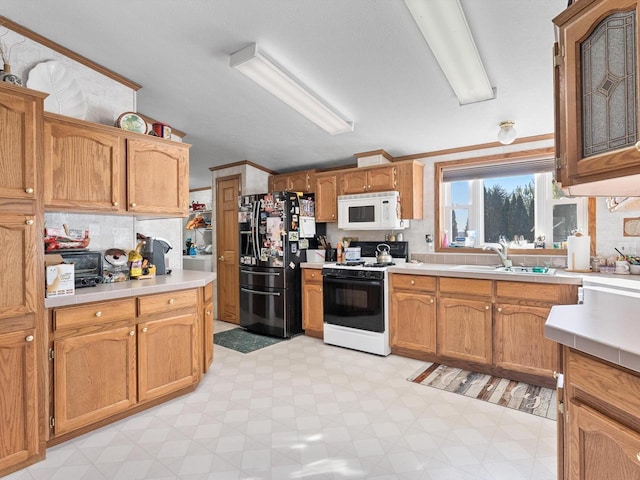 kitchen with sink, range with gas cooktop, crown molding, black refrigerator with ice dispenser, and decorative backsplash