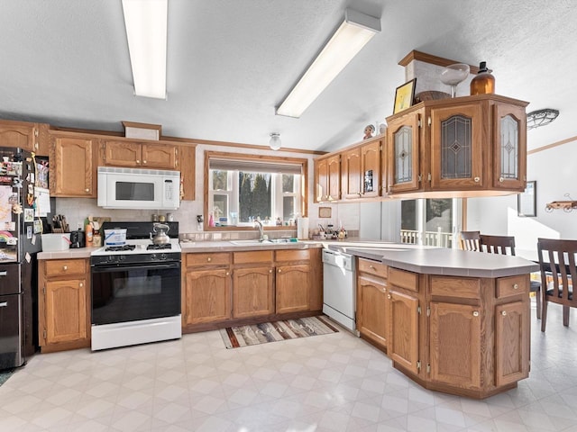 kitchen featuring lofted ceiling, sink, white appliances, decorative backsplash, and kitchen peninsula