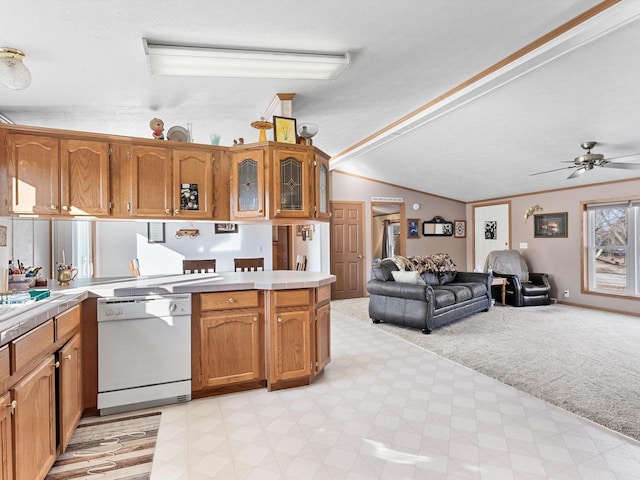 kitchen featuring ceiling fan, white dishwasher, vaulted ceiling, light colored carpet, and kitchen peninsula