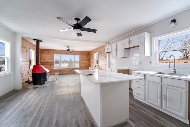 N3005 Lakeview Dr, Montello, WI 53949 - kitchen featuring sink, wooden walls, white cabinets, dark hardwood / wood-style flooring, and a wood stove