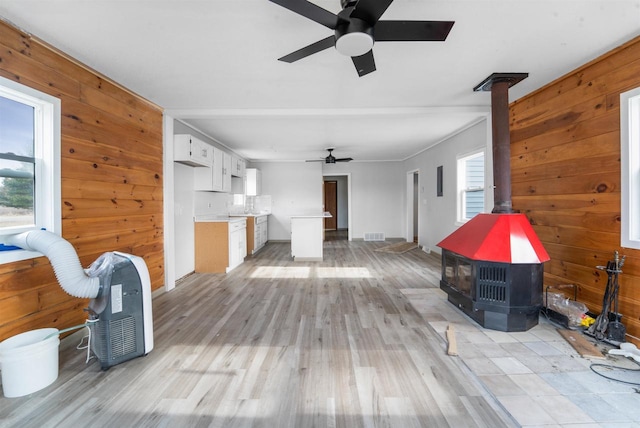 N3005 Lakeview Dr, Montello, WI 53949 - living room with ceiling fan, a wood stove, wooden walls, and light hardwood / wood-style flooring