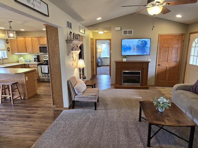 living room featuring dark hardwood / wood-style floors, lofted ceiling, sink, and ceiling fan