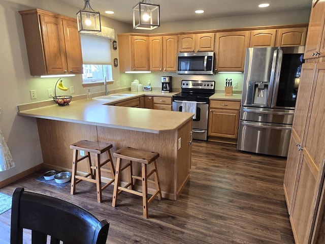 kitchen with appliances with stainless steel finishes, decorative light fixtures, sink, a kitchen breakfast bar, and kitchen peninsula