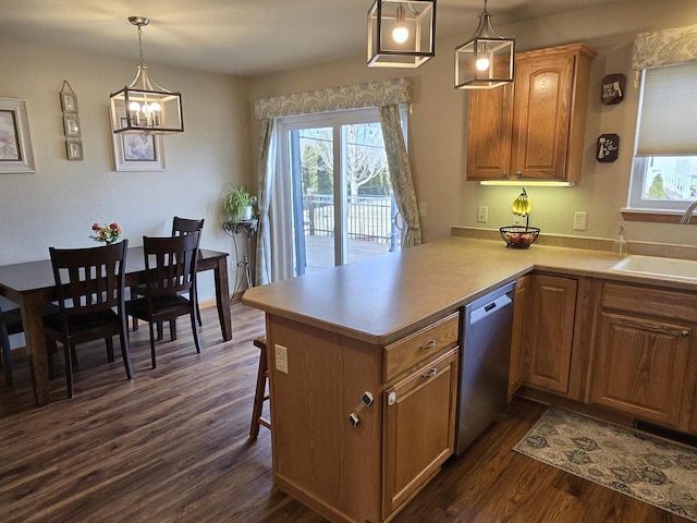 kitchen with pendant lighting, sink, dark hardwood / wood-style flooring, stainless steel dishwasher, and kitchen peninsula