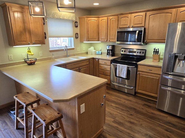 kitchen featuring sink, a kitchen breakfast bar, kitchen peninsula, stainless steel appliances, and dark wood-type flooring