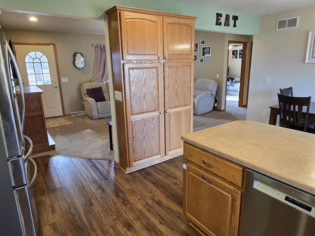 kitchen with dark wood-type flooring, dishwashing machine, and stainless steel refrigerator