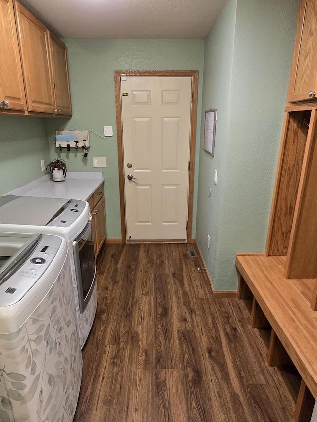 laundry room with cabinets, dark hardwood / wood-style floors, and washing machine and clothes dryer