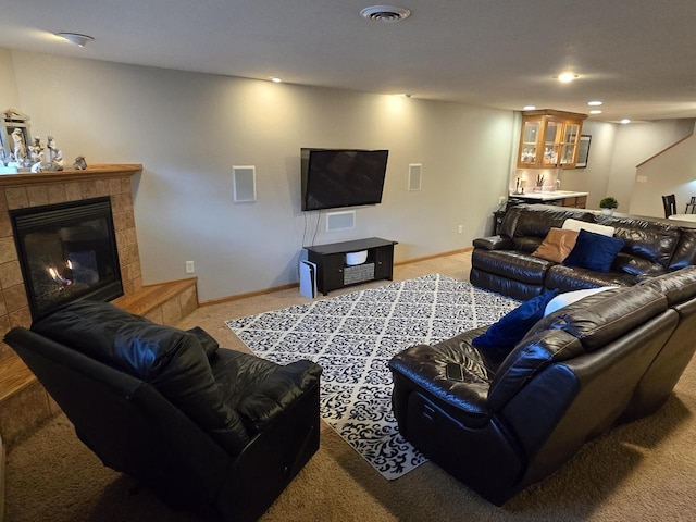 living room featuring light carpet, a tile fireplace, and bar area