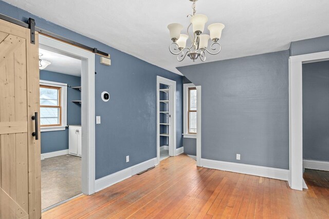 1033 Vernon St, Stoughton, WI 53589 - unfurnished room featuring wood-type flooring, a barn door, and a chandelier