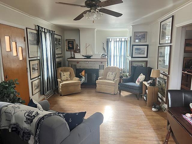 living room featuring light hardwood / wood-style flooring, ornamental molding, and ceiling fan