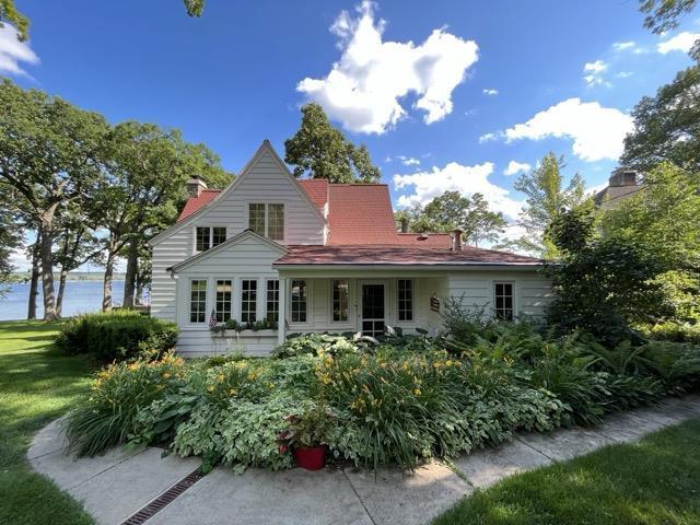 back of house featuring a water view and a lawn