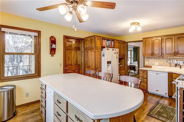 kitchen with a kitchen island, backsplash, white appliances, and light hardwood / wood-style floors