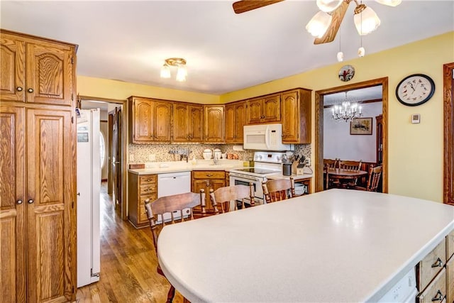 kitchen featuring hardwood / wood-style flooring, white appliances, ceiling fan, and backsplash