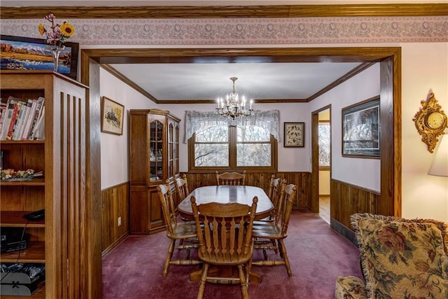 dining space with crown molding, an inviting chandelier, and dark carpet