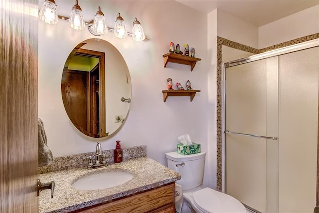 bathroom featuring toilet, vanity, and walk in shower