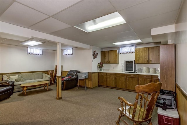 kitchen featuring light carpet, a drop ceiling, and wood walls