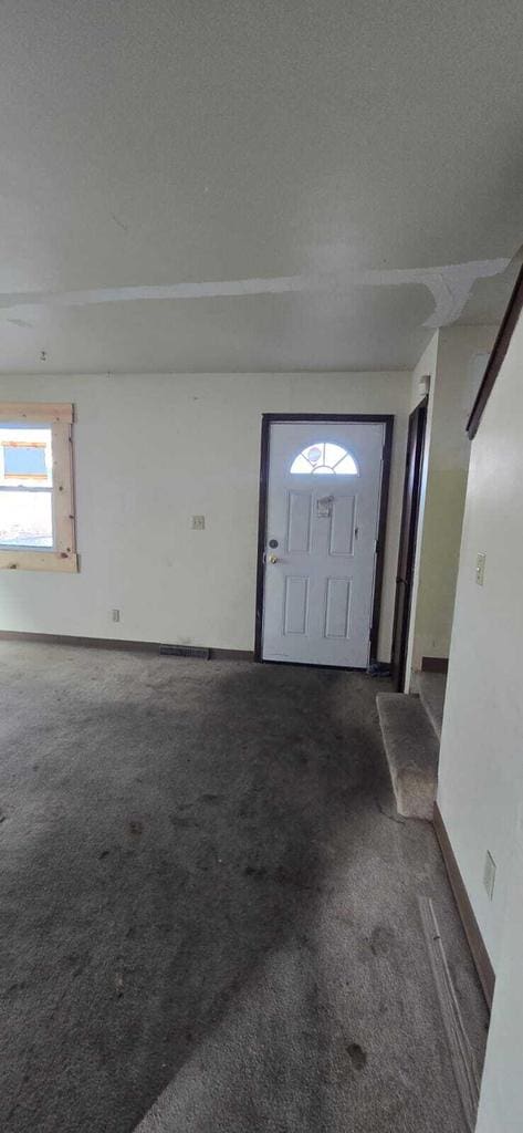 entrance foyer with dark carpet and a textured ceiling