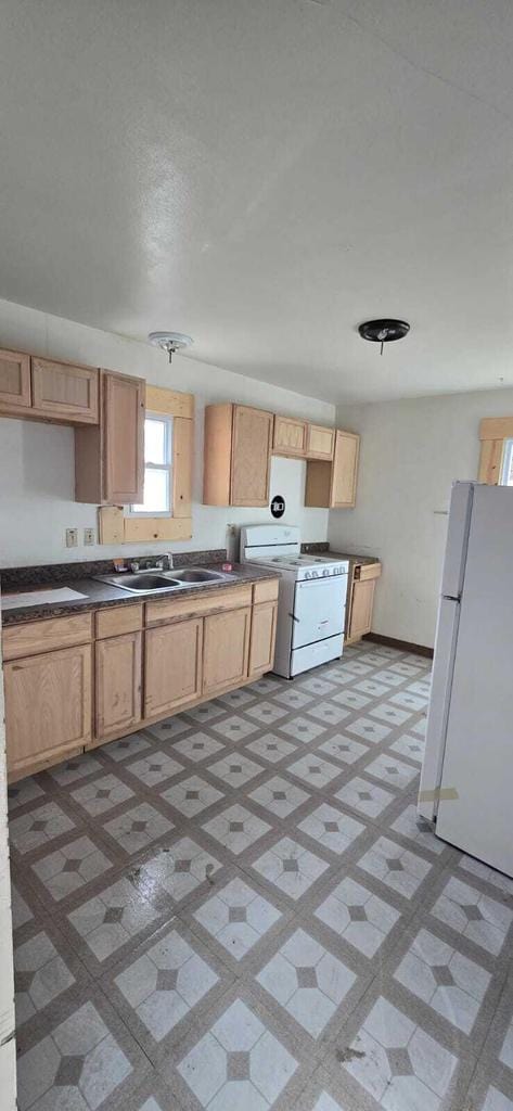 kitchen with white appliances, light brown cabinetry, and sink