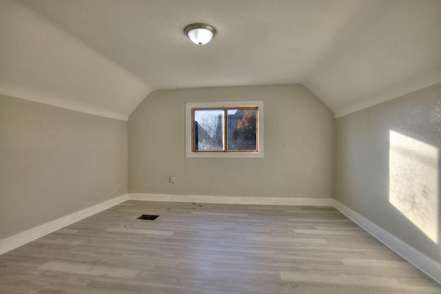 bonus room with vaulted ceiling and light wood-type flooring