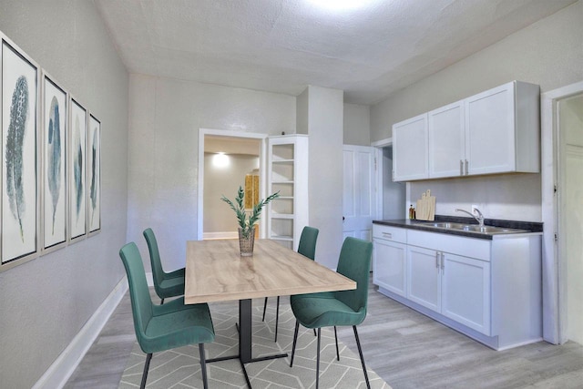 dining room featuring sink, light hardwood / wood-style flooring, and a textured ceiling