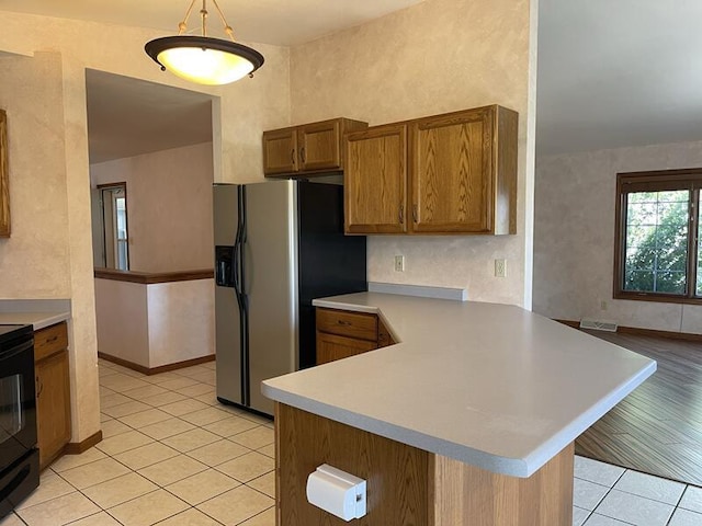 kitchen featuring pendant lighting, stainless steel fridge with ice dispenser, kitchen peninsula, and light tile patterned flooring