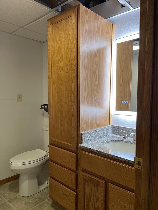 bathroom featuring vanity, a paneled ceiling, tile patterned floors, and toilet