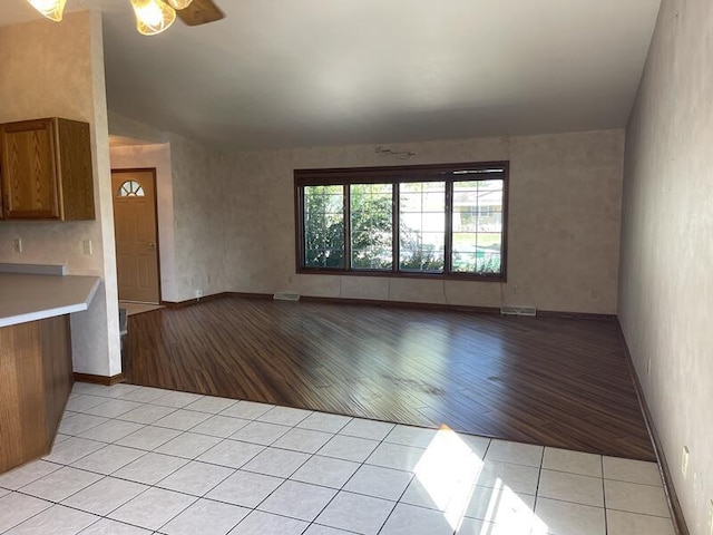 unfurnished living room featuring vaulted ceiling, light tile patterned floors, and ceiling fan