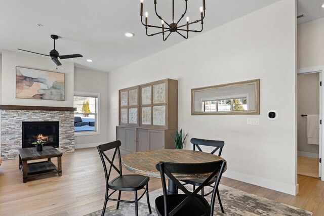 dining area with baseboards, a stone fireplace, recessed lighting, and light wood-style floors