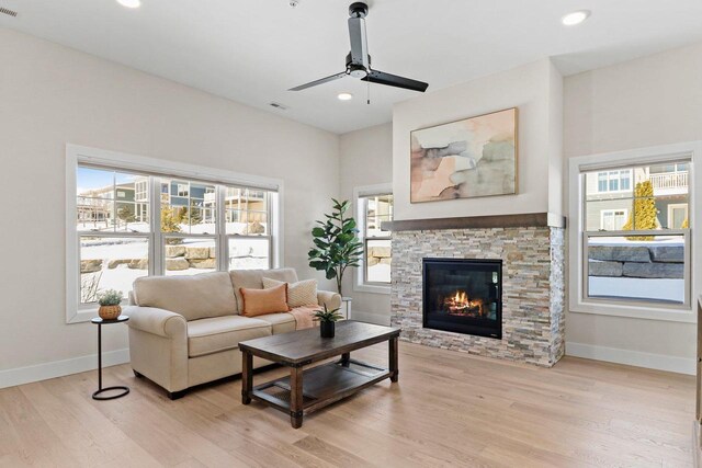 living room with light wood-type flooring, a fireplace, baseboards, and recessed lighting