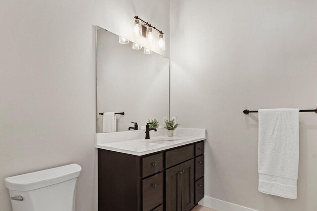 bathroom with baseboards, vanity, and toilet