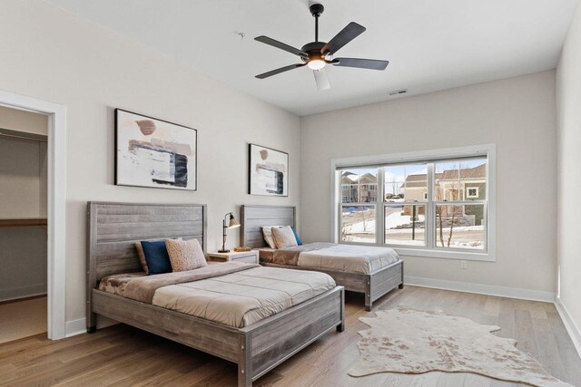 bedroom with ceiling fan, light wood finished floors, and baseboards