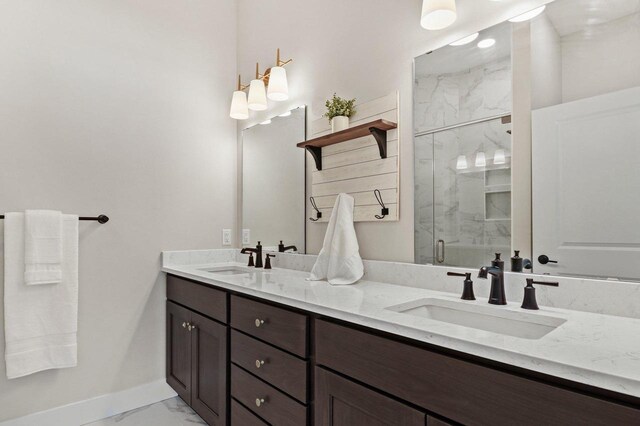 full bath with marble finish floor, a sink, a marble finish shower, and double vanity