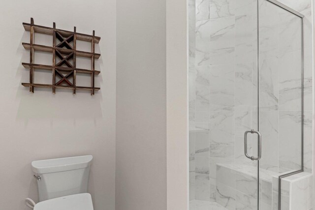 bathroom with toilet and a marble finish shower