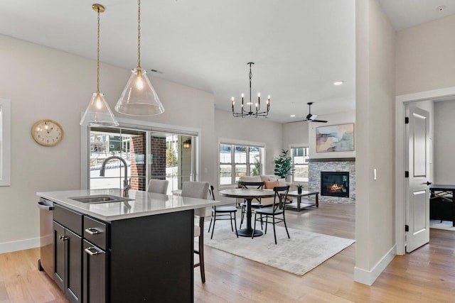 kitchen featuring light wood finished floors, a center island with sink, open floor plan, light countertops, and a sink