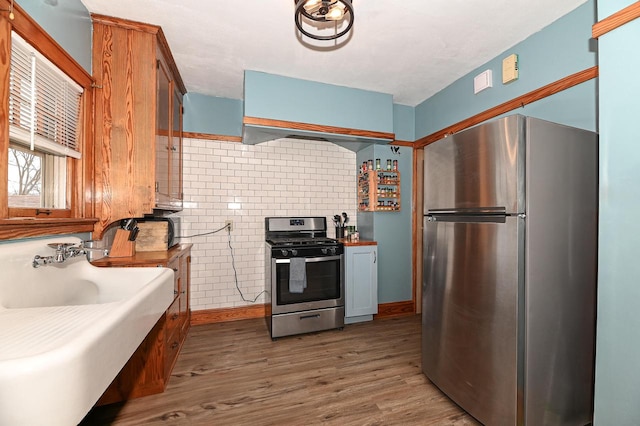 kitchen featuring sink, exhaust hood, dark hardwood / wood-style floors, and appliances with stainless steel finishes